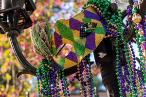 Outdoor Mardi Gras beads and mask on light post in sunshine